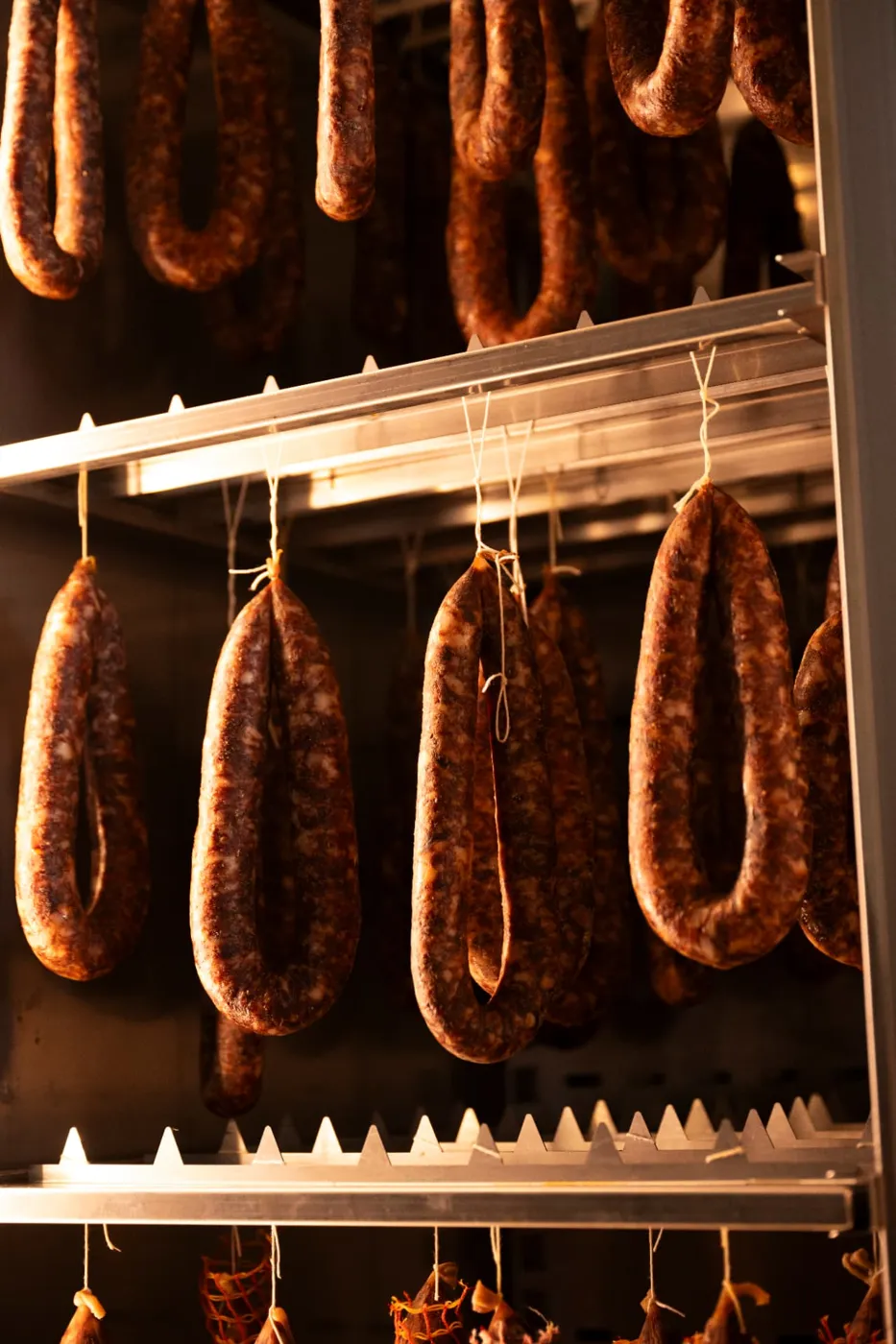Salumi appesi in stagionatura nel laboratorio aziendale