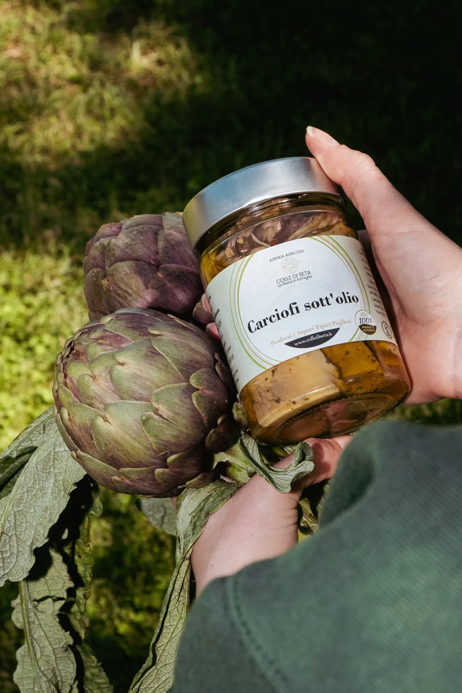 Vasetto di carciofi sott’olio accanto ai carciofi freschi