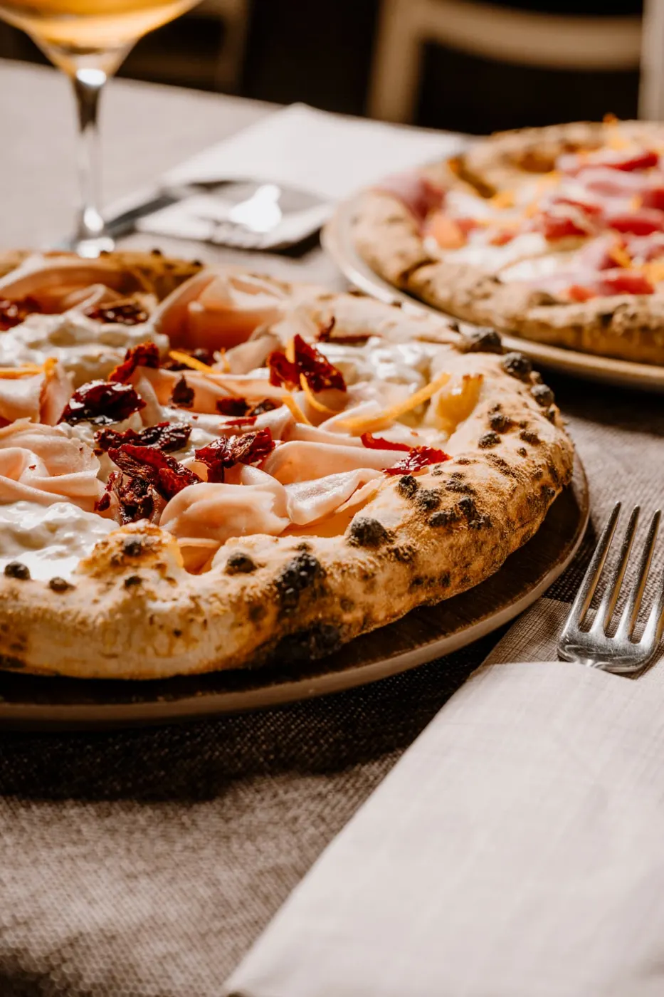 Pizza con mortadella, stracciatella e pomodori secchi servita in sala