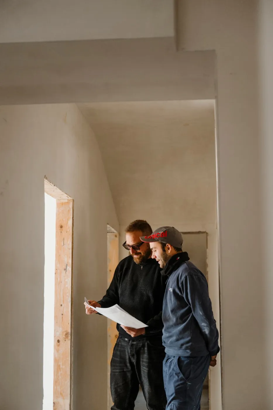 Architetto e operaio consultano un disegno tecnico in un ambiente in costruzione