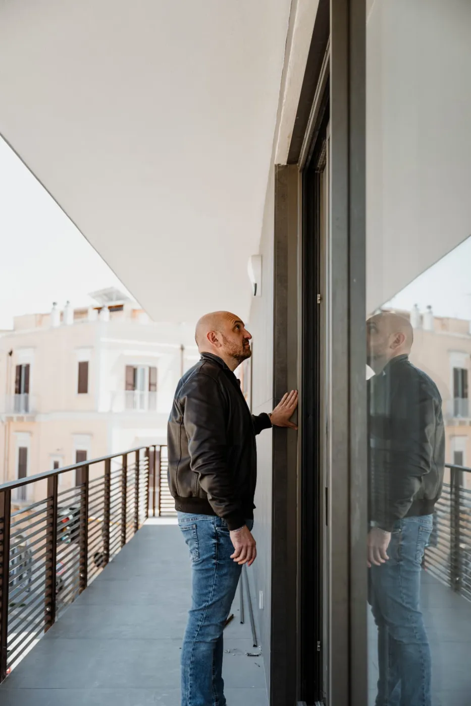 Architetto osserva il serramento di un balcone riflesso nella vetrata