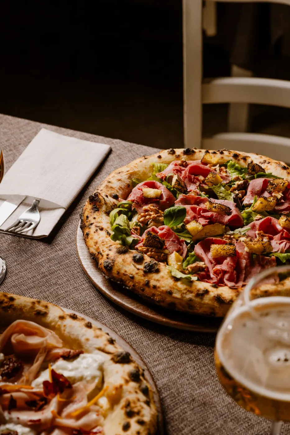 Pizza con roast beef, insalata e noci su tavola apparecchiata