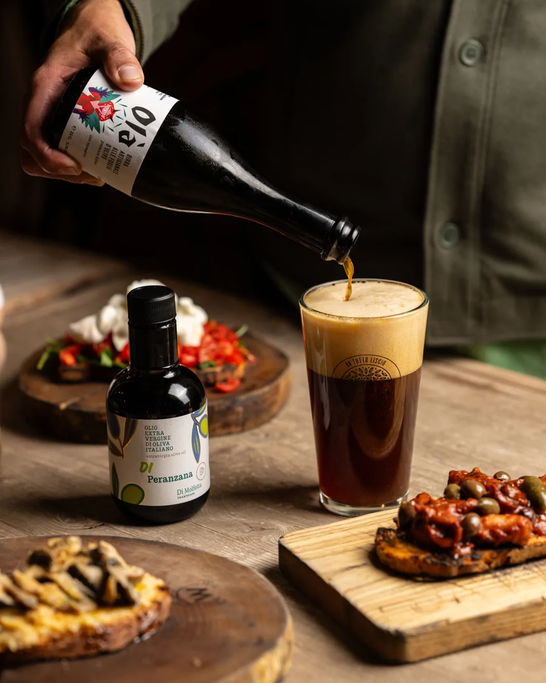 Birra artigianale alle foglie d’olivo versata accanto all’olio Peranzana